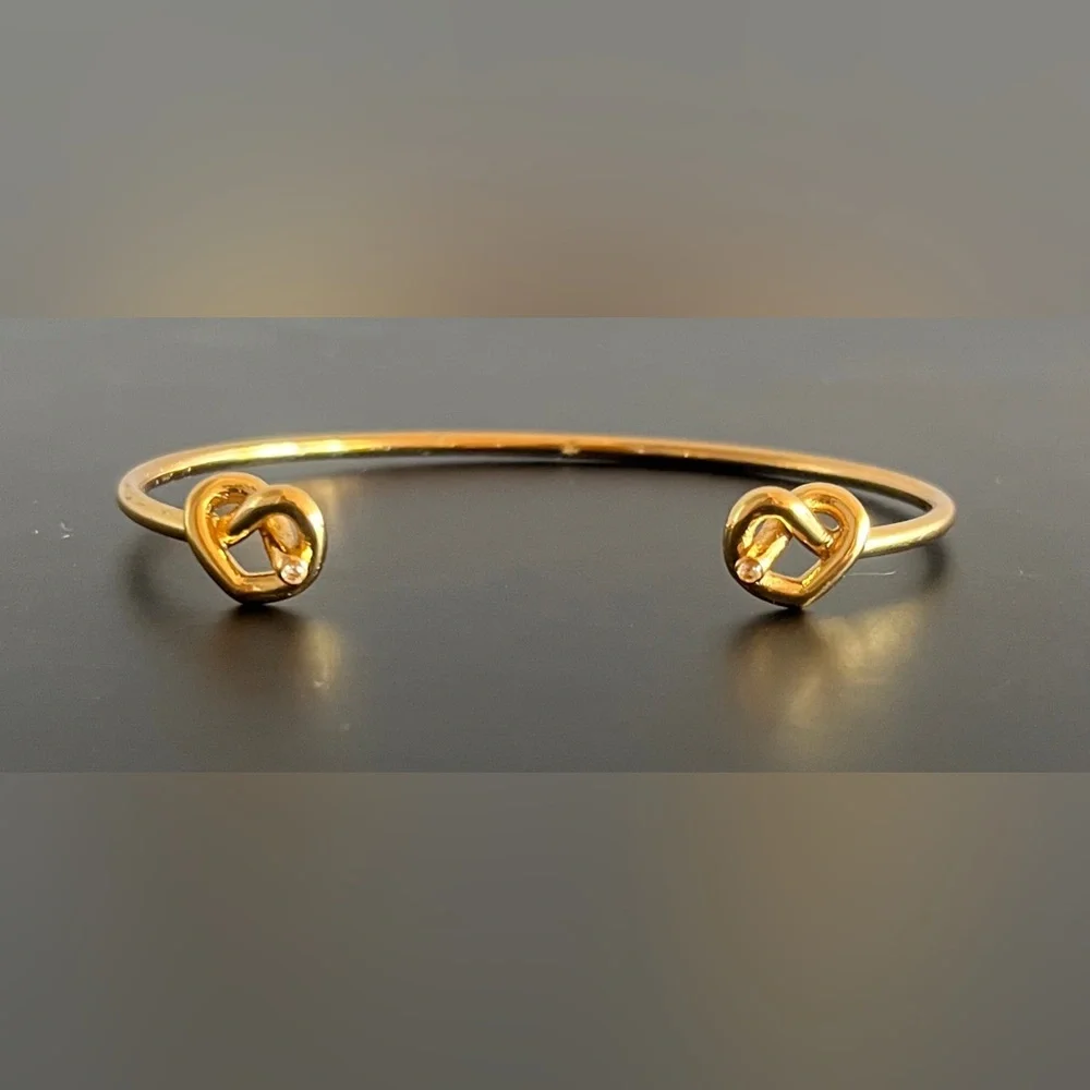Kate Spade New York Loves Me Knot Cuff bangle in gold-tone w knot-accented ends.